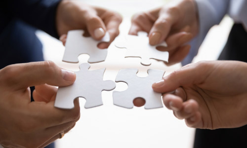 Hands bringing puzzle pieces together together 